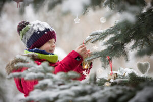 boy decorating snowy tree