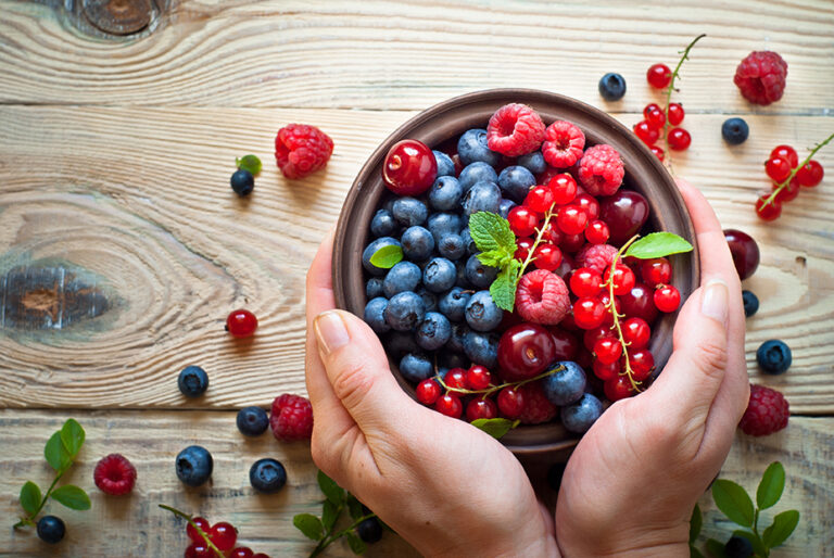 fresh summer berries in bowl with hands