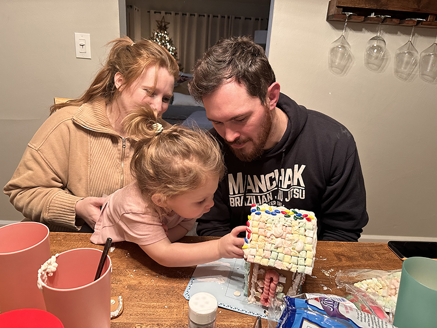 Family decorating a gingerbread house together