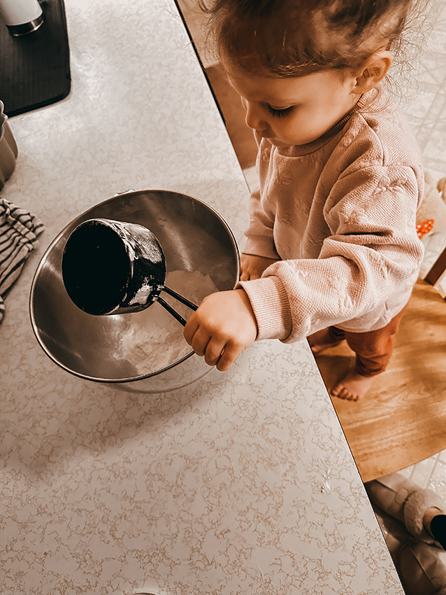 Child pouring flour into bowl for cake