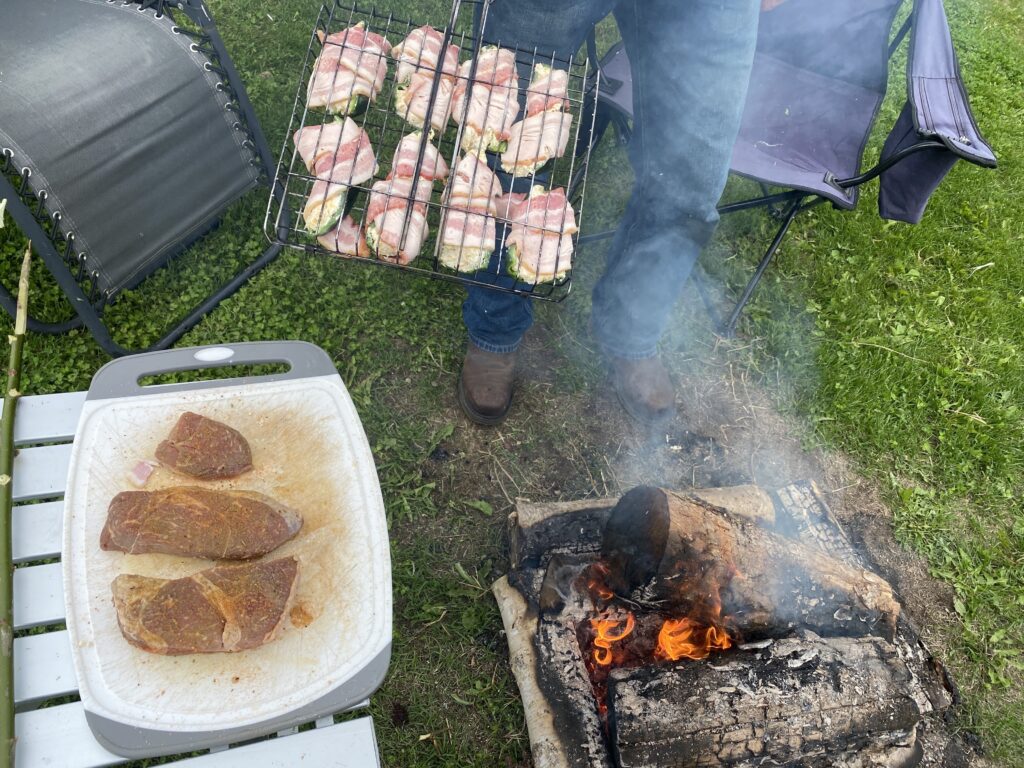 Cooking steaks and jalapeno poppers over campfire