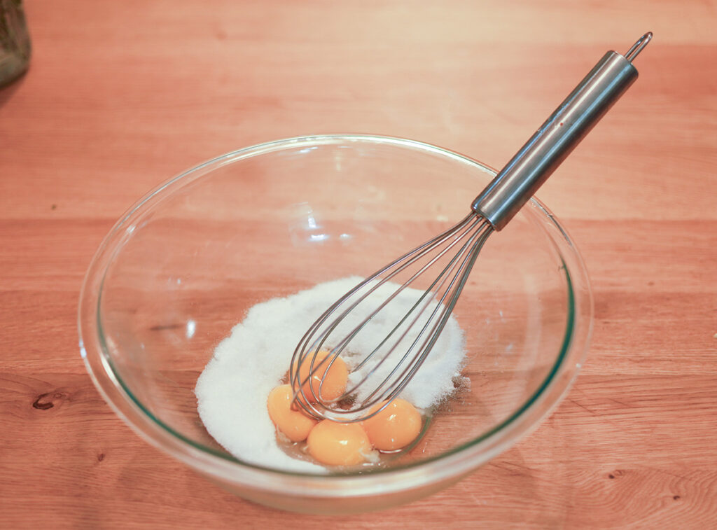 whisking egg yolks with sugar in a bowl