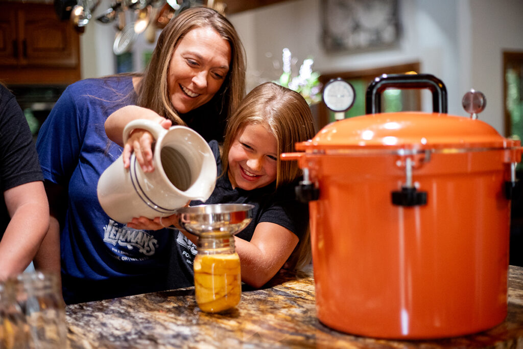 Family canning peaches together with All American Canner