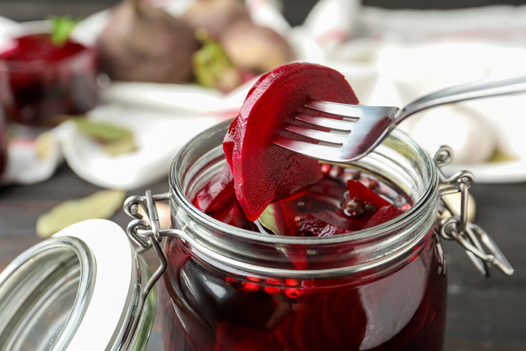 Fork lifting pickled red beets out of jar