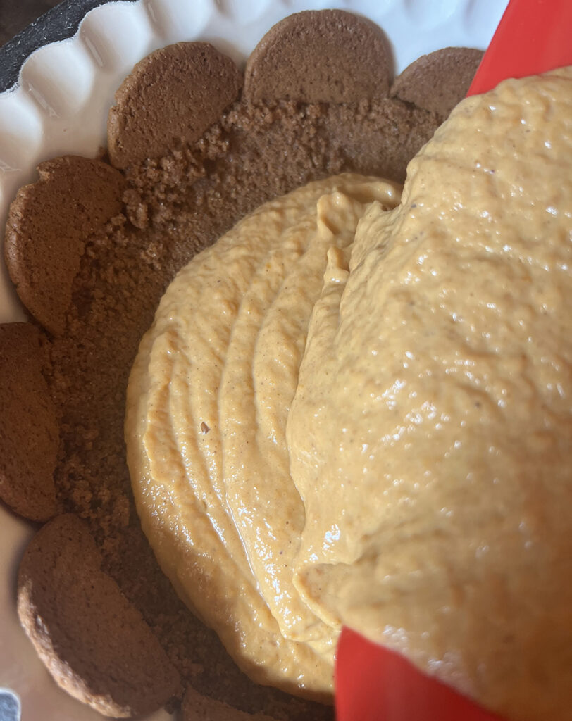 Pouring pumpkin filling into pie crust