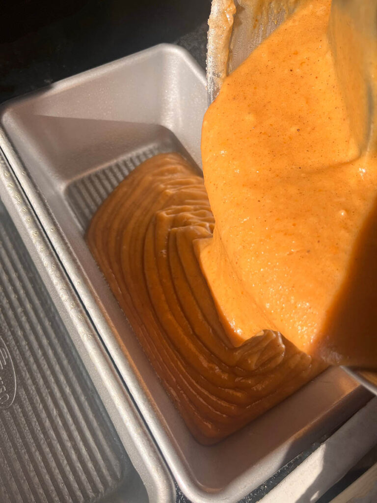 Pouring pumpkin bread batter into loaf pans